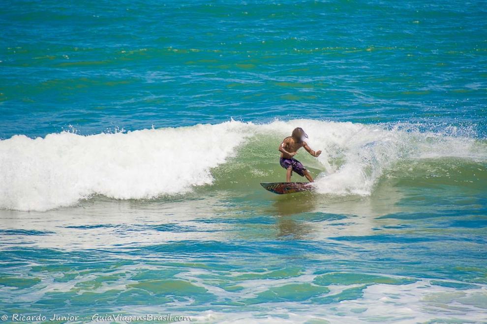 Imagem de surfistas de equilibrando nas ondas da praia.